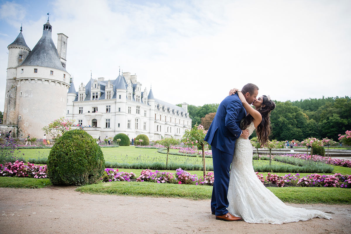 A bride and groom kiss outside Château de Chenonceau, France on their wedding day