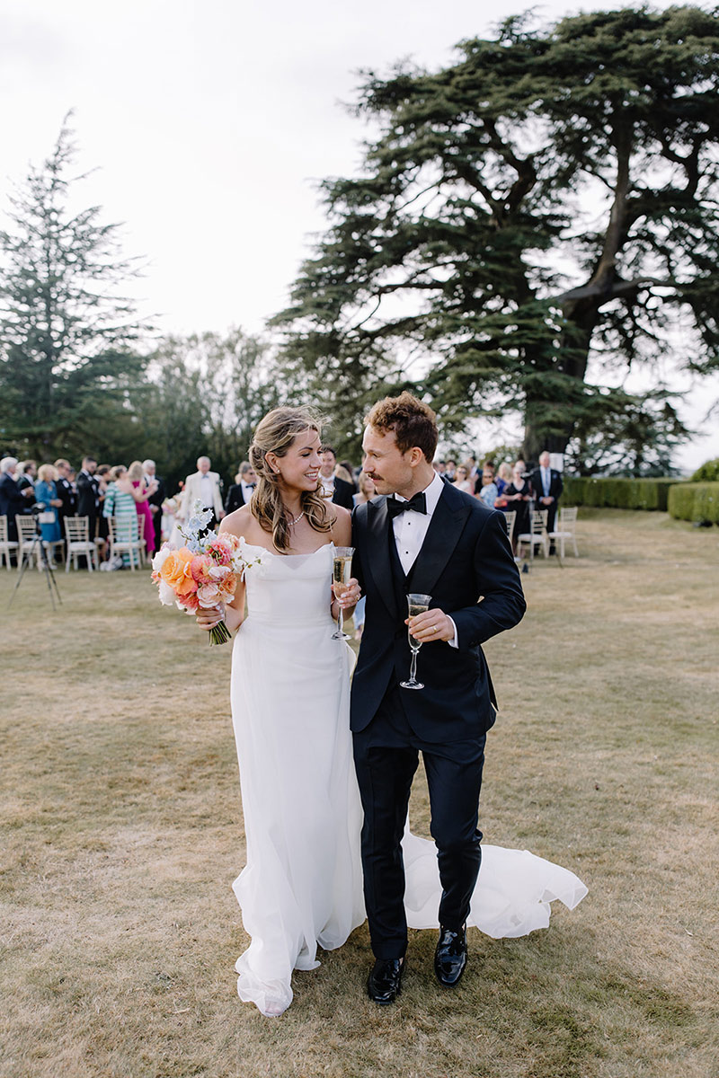 A wedding couple walk away from their outdoor ceremony in the UK