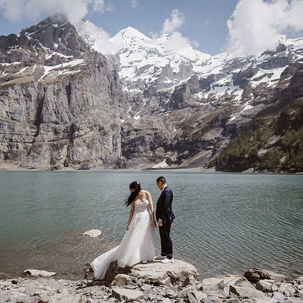 A bride and groom stand on the shores of Lake Oeschinensee after saying their vows on their Elopement wedding in Switzerland