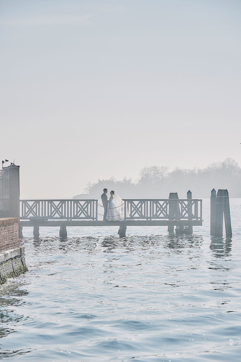 A bride and groom stand on a pontoon in Venice Italy during a styled shoot