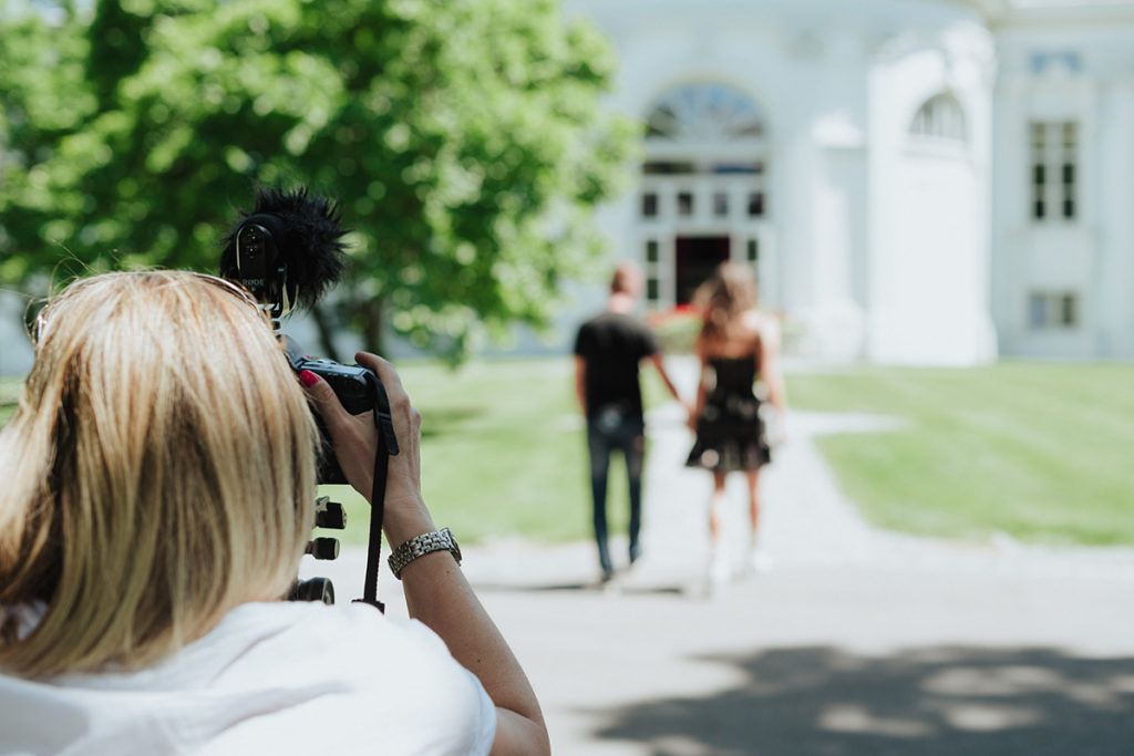View from behind of Emma Wilson from Story Of Your Day filming a couple walking away from her in Switzerland