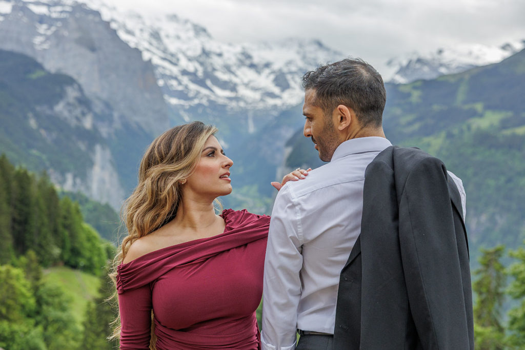 A bride in a red dress gazes into her grooms eyes above Luterbrunnen in Switzerland