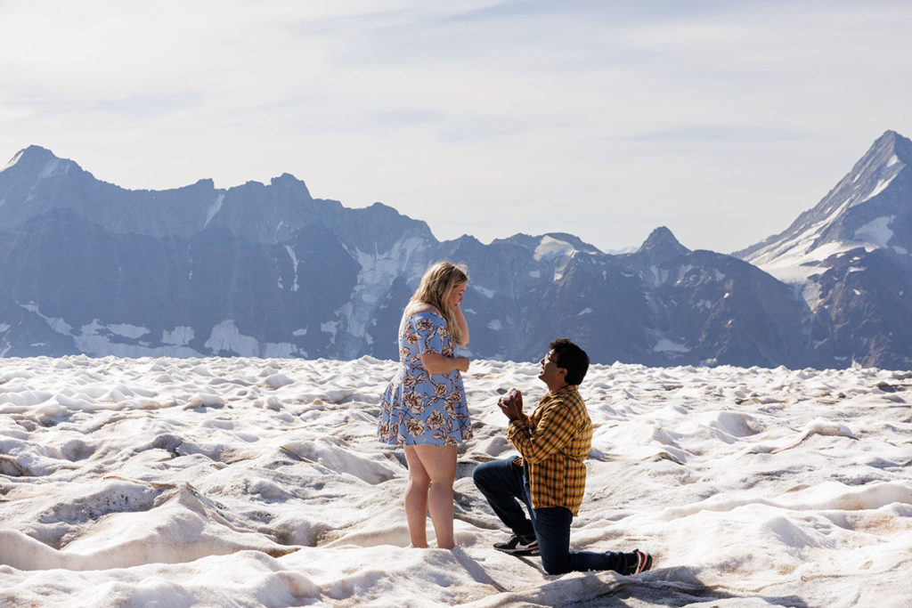Man on one knee proposing to woman on snow-capped glacier in Switzerland photographed by Story Of Your Day
